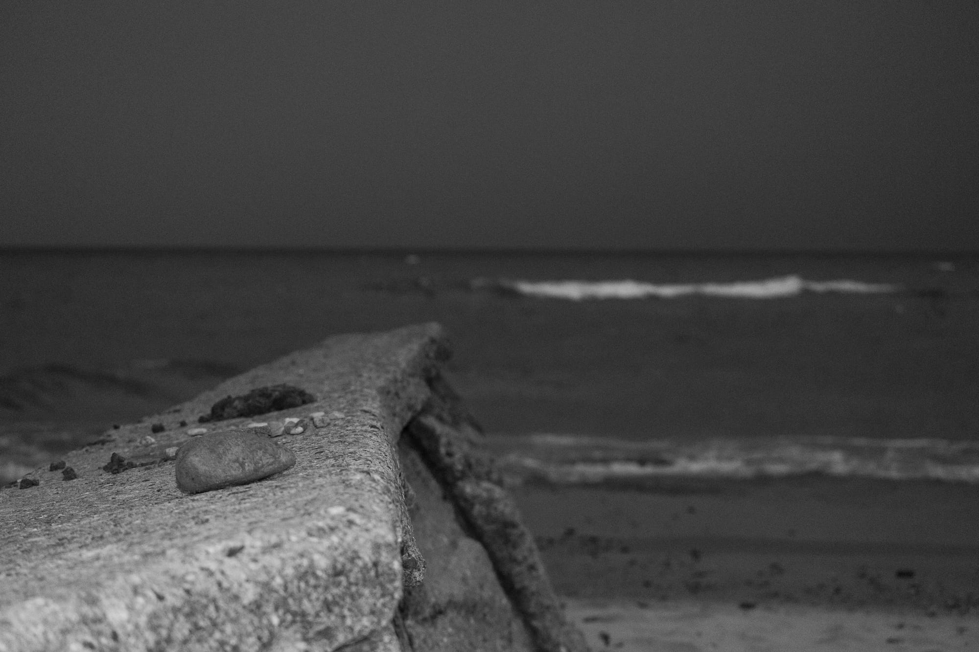 A moody picture of a concrete barrier on the beach.