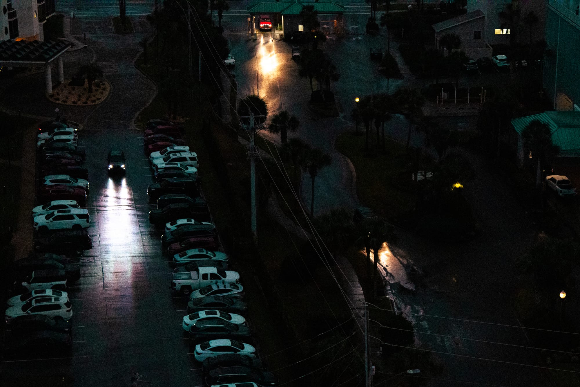Cars driving in the dark, their headlights reflecting off the wet asphalt.